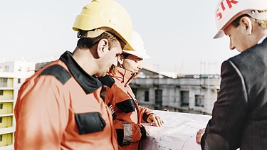 Bild des STRABAG-Teams auf einer Baustelle bei der Besprechung von Plänen