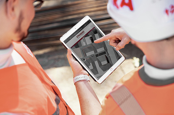 Picture of STRABAG BIM specialists looking at a tablet.