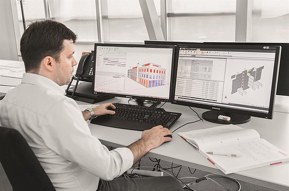 Picture of a STRABAG employee working at his desk and looking at his computer