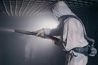 Photo d'un ouvrier de TORKRET en tenue de protection pour pulvériser du béton.